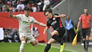 Augsburg's Mert Kömür (L) and Frankfurt's Arthur Theate challenge for the ball during the match at the WWK Arena, Augsburg, Germany,  April 20, 2025. (AP Photo)